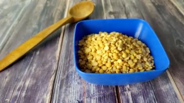 Split peas close-up in a blue bowl on a wooden table.  Shooting from above