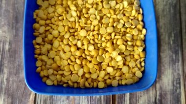 Split peas close-up in a blue bowl on a wooden table.  Shooting from above