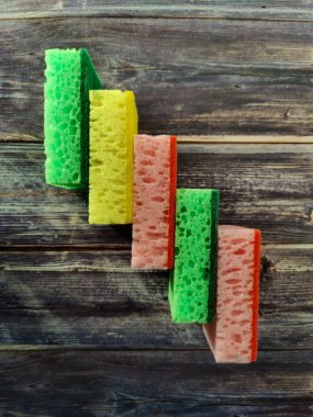 Multi-colored kitchen sponges for washing dishes on a wooden table.  View from above 