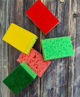 Multi-colored kitchen sponges for washing dishes on a wooden table.  View from above 