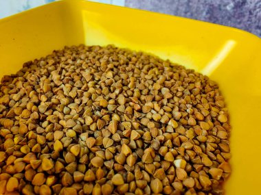 Raw buckwheat in a yellow plastic bowl.  Cereals.  Bulk products