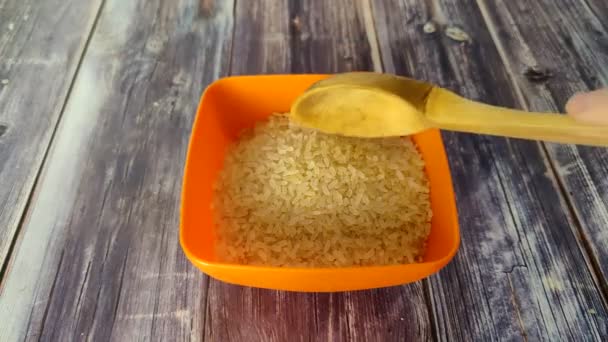 Wooden Spoon Scoops Uncooked Rice Orange Plastic Dish Close — Stock video