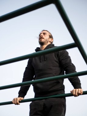 Caucasian man doing muscle up outdoor in the calisthenics park