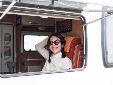 İspanyol esmer kadın karavanda oturuyor ve gülümsüyor.
