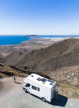 Man standing by his motor home looking at nice views from top of the mountain at Puntas de Calnegre, Murcia clipart