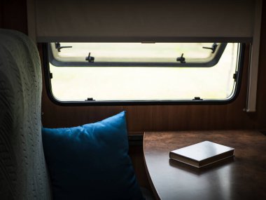 Karavan penceresinin yanındaki masada beyaz bir kitap.