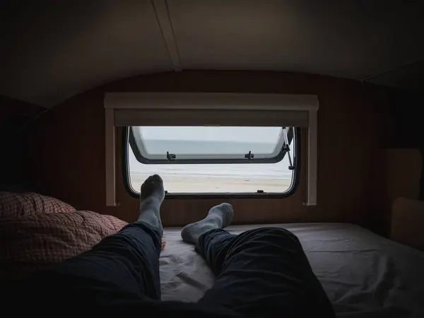 Karavanın penceresinden kumsala sabah manzarası yayılıyor.