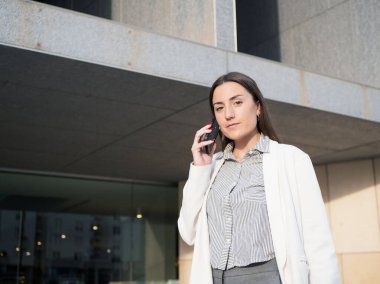 Şehir merkezinde ofis dışında akıllı telefon kullanan profesyonel bir kadın.