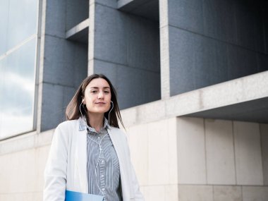 Kendine güveni tam bir iş kadını, modern binanın dışında dinleme cihazı ile yürüyor.