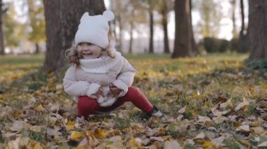 Sonbahar parkında yaprakları olan küçük bir kız. Yavaş çekim
