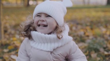 Sonbahar parkında yaprakları olan küçük bir kız. Yavaş çekim