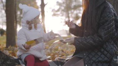 Anne ve küçük çocuk bir sonbahar parkında ellerinde bir kitapla, mutlu bir aile, anneyle yaşamak, doğa yürüyüşü.
