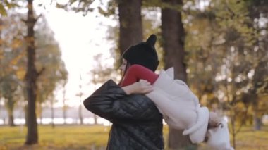 Anne ve küçük çocuk sonbahar parkında. Mutlu bir aile, anneyle yaşamak, neşeli bir çocuk, annesinin omuzlarında oturmak, doğa yürüyüşü.