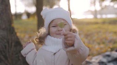 Küçük bir kız parkta bir çubukta şeker yiyor. Şekerli çocuk. Mutlu bebek yüzlü. Lolipoplu mutlu çocuk