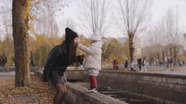 Mutlu aile, genç anne ve kız sonbahar parkında yürüyorlar. Anneler Günü