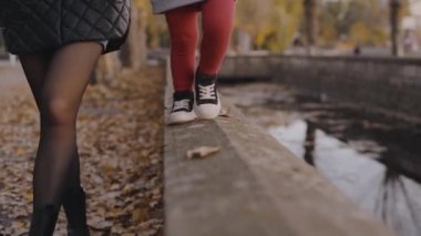 Mutlu aile, genç anne ve kız sonbahar parkında yürüyorlar. Anneler Günü