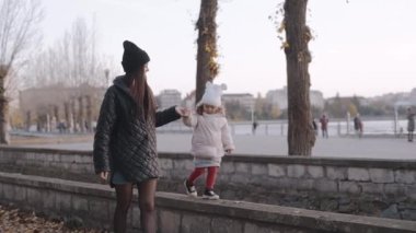 Mutlu aile, genç anne ve kız sonbahar parkında yürüyorlar. Anneler Günü
