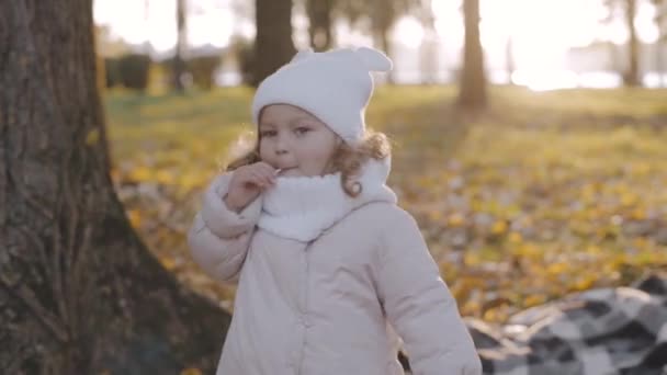 女の子は公園の棒でお菓子を食べる キャンディの子だ 幸せな赤ん坊の顔 幸せな子供とともにロリポップ — ストック動画