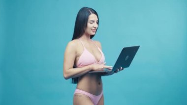 Beautiful woman smiling with laptop enjoying their summer vacation on blue background. Happy trip concept