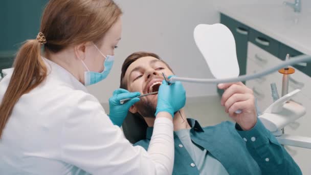 女牙医在牙科治疗牙齿 一个手里拿着牙镜的病人 — 图库视频影像