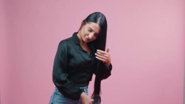 Business woman in black blouse combing hair posing isolated on pink background. Working content