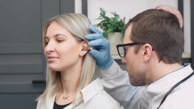 Erkek otolarolog, modern hastanedeki erkek hastaların kulaklarını inceliyor.