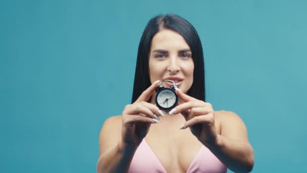 美丽的女人带着时钟微笑 带着蓝色背景享受暑假 — 图库视频影像