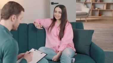 Koltukta oturan genç bir psikologun omuz üstü fotoğrafı ve danışma seansı sırasında dikkatle dinleyen bir kadın.