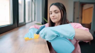 Ev kadınının mavi lastik eldivenli yakın çekimi yıkama, oda tezgahındaki pencere pervazına deterjanla ıslak sarı bir bez püskürtme.