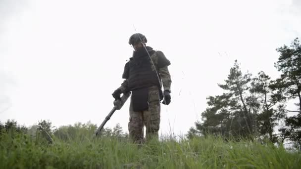 森の近くの草の中で地雷を探知しようとしてる スローモーション — ストック動画