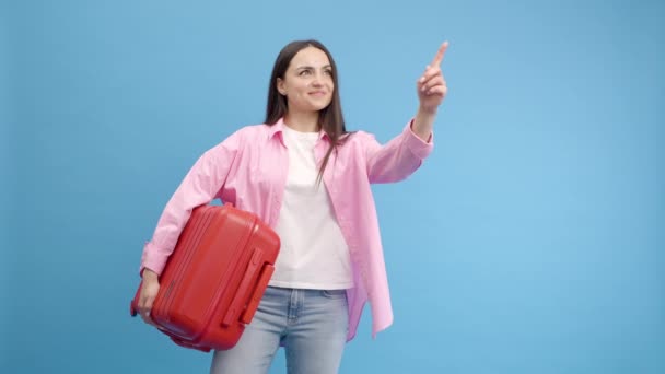 Usmívající Žena Dělá Reklamu Studiu Modrém Pozadí Červeným Kufříkem Ukazuje — Stock video