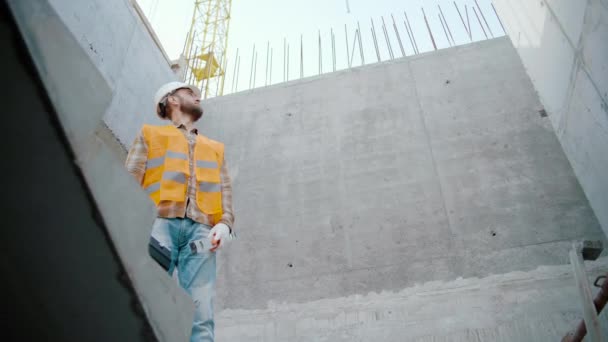 建設現場でツールボックスとバブルレベルのツールを持つ男性労働者は側面に見えます スローモーション — ストック動画
