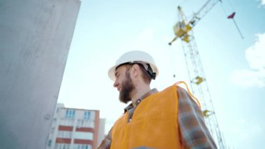 İnşaat alanındaki yorgun bir işçi çok çalıştıktan sonra elini duvara dayar ve stres altındadır. Güneşli bir yaz gününde yol inşaatında çalışan bir işçi.