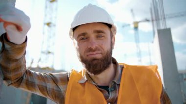 İnşaat alanındaki yorgun bir işçi çok çalıştıktan sonra elini duvara dayar ve stres altındadır. Yakın plan. Güneşli bir yaz gününde yol inşaatında çalışan bir işçi.