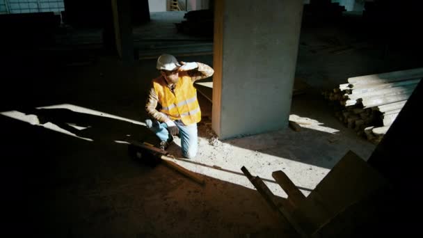 建設労働者は壁の近くに座り 工事現場で工具箱を開ける 男の影 スローモーション — ストック動画