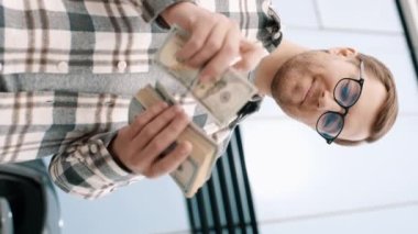 Adam arabanın yanında dolarları sayıyor. Erkek eli kapalı para saymak. Kazanç ya da rüşvet kavramı, sigorta ya da kredi, yatırım. Lüks arabada para sayan bir adam.
