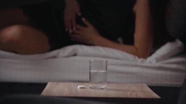 Karın ağrısı çeken hasta bir kadın, bir bardak su, ilaç ve sağlık hizmetleri konseptine coşkulu bir köpürtücü tablet koyuyor.