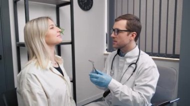 Modern hastanede otoskopla burun muayenesi yapan profesyonel bir erkek doktor. Burun tıkanıklığı, sinüzit, alerji konsepti.