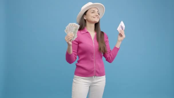 戴白帽子的女孩拿着护照 机票和钱 在工作室里享受着蓝色的背景 慢动作 — 图库视频影像