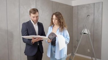 Yeni evin planlarını arayan gülümseyen insanlar. Neşeli aile aydınlık odada tasarım projesi üzerinde çalışıyor.