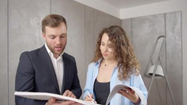 Yeni evin planlarını arayan gülümseyen insanlar. Neşeli aile aydınlık odada tasarım projesi üzerinde çalışıyor.