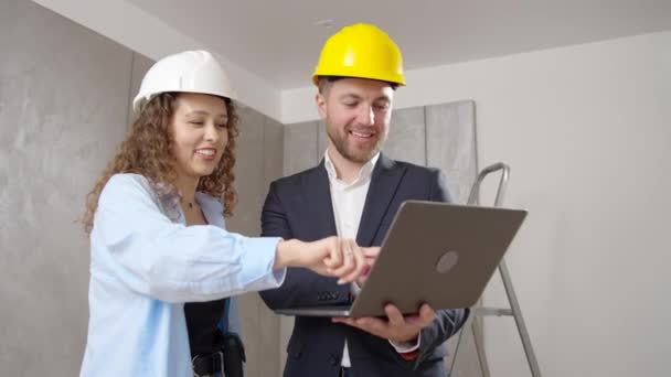 建築家 若い男性と女性は 屋内改修中に壁を塗装するためにコンピュータ上の部屋のデザインを選択します — ストック動画