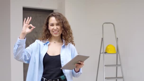 タブレット付きの若い女性建築家は 新しいデザイナーアパートでOkを示しています スローモーション — ストック動画