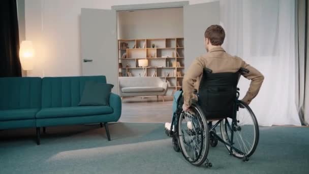 Siguiendo Shot Young Smilling Man Wheelchair Moverse Través Habitación Macho — Vídeo de stock