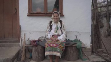 Ukrayna sembollerinde yaşlı bir kadın eski bir evin yanında oturuyor.