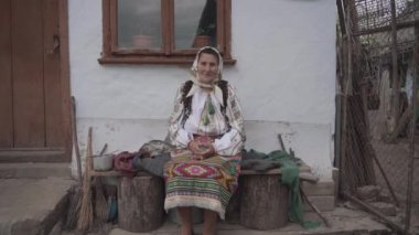 Ukrayna sembollerinde yaşlı bir kadın eski bir evin yanında oturuyor.
