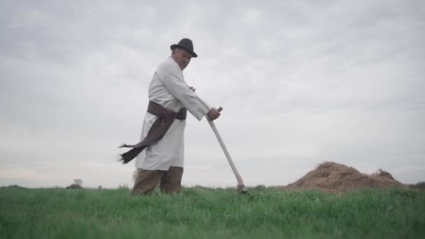Seorang Pria Tua Dalam Kemeja Bordir Ukraina Memotong Rumput Lapangan — Stok Video