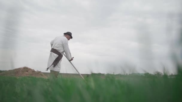 一位穿着乌克兰绣花衬衫的老人在田里割草 慢动作 — 图库视频影像