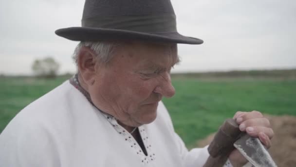 Yaşlı Adam Tarlada Eski Bir Tırpanı Keskinleştirir Kameraya Bak Yavaş — Stok video