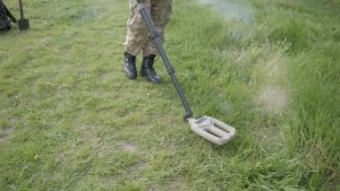 Military sapper with a metal detector in the field. Ukrainian Explosive Ordnance Disposal Officer detecting metal by metal detector device